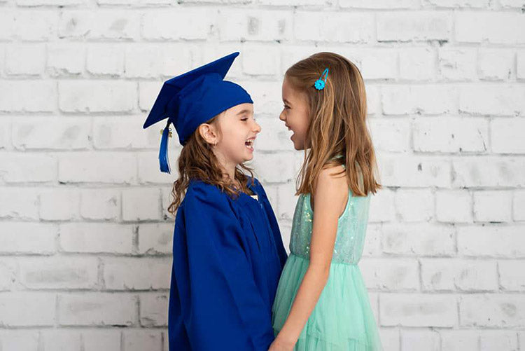 sisters smiling at each other standing in front of the white brick wall backdrop