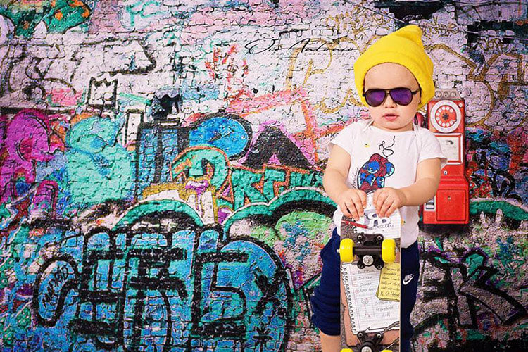 little fashion boy standing in front of a graffiti wall