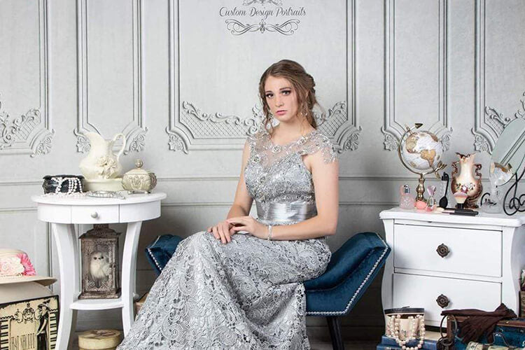 A woman sitting in front of a grey wall backdrop