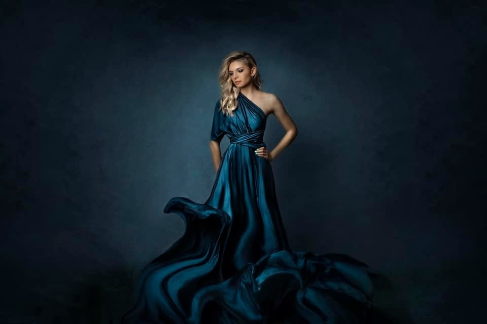 A woman standing in front of a blue black abstract texture backdrop