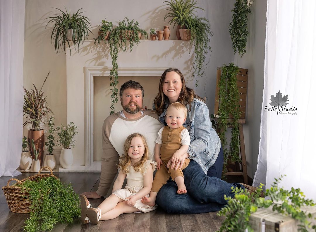 Family sitting on the floor in front of the spring fireplace backdrop