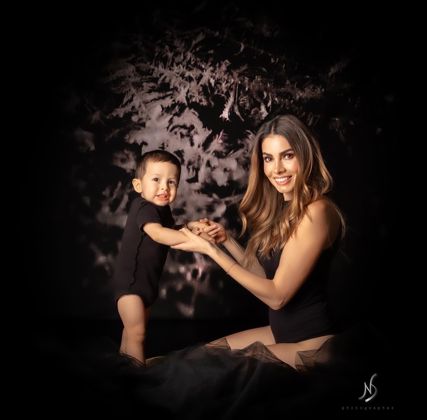 Mother and son sitting in front of a black abstract textured backdrop