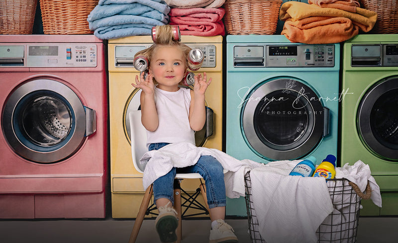 Little girl sitting on the chair in front of washing machine backdrop
