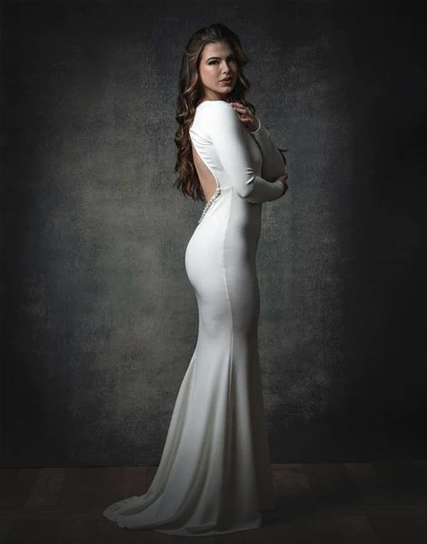 A woman in white dress standing in front of a black abstract backdrop